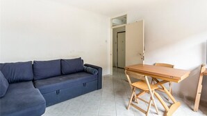 A room with a dark blue sofa, a wooden table with chairs, and a door leading to another room. - Central one bedroom flat. CONTACT ME BEFORE BOOKING TO CHECK AVAILABILITY (London)