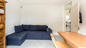 A compact living space with a dark-colored sofa, a wooden table, and a bookshelf. - Central one bedroom flat. CONTACT ME BEFORE BOOKING TO CHECK AVAILABILITY (London)