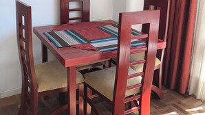 A dining area with a wooden table and chairs, a framed picture on the wall, and red curtains. - Private Apartment on Arce Avenue (La Paz)