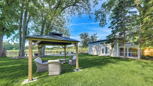 A covered outdoor seating area with wicker furniture, a small building, and a well-maintained lawn. - Lakefront Antioch Home w/ Dock, Grill, Game Room! (Antioch)