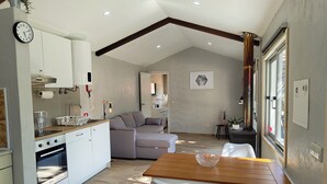 A modern kitchen with white cabinets, a built-in oven, and a dining area with a wooden table and white chairs.