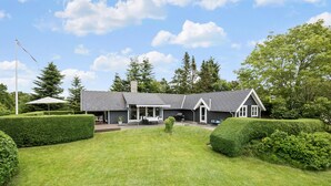 A modern house with a covered patio, a lawn, and neatly trimmed hedges. - 2 bedroom beautiful home in Farsø (Farsø)