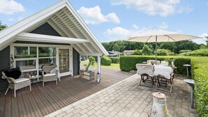 A covered outdoor patio with wicker furniture, a table with a white fur throw, and a large umbrella. - 2 bedroom beautiful home in Farsø (Farsø)