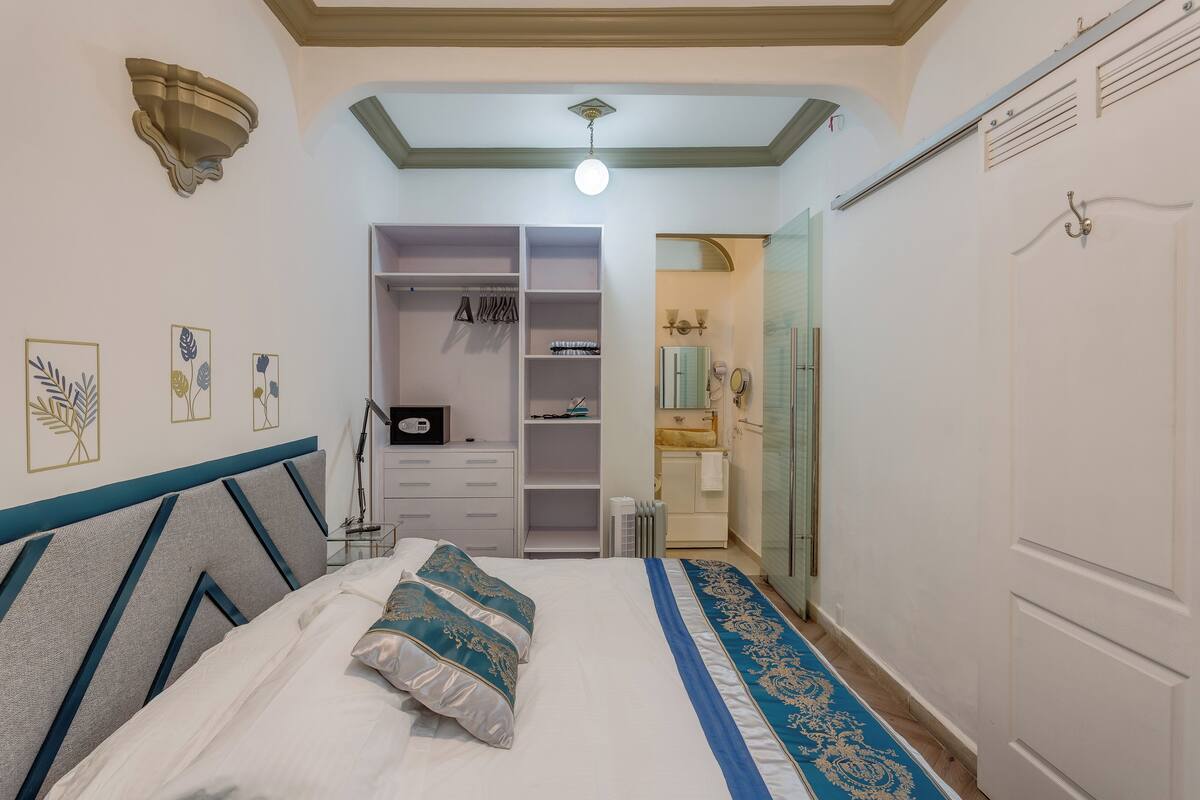 A bedroom with a bed, a wardrobe, a vanity with a mirror, and a radiator.