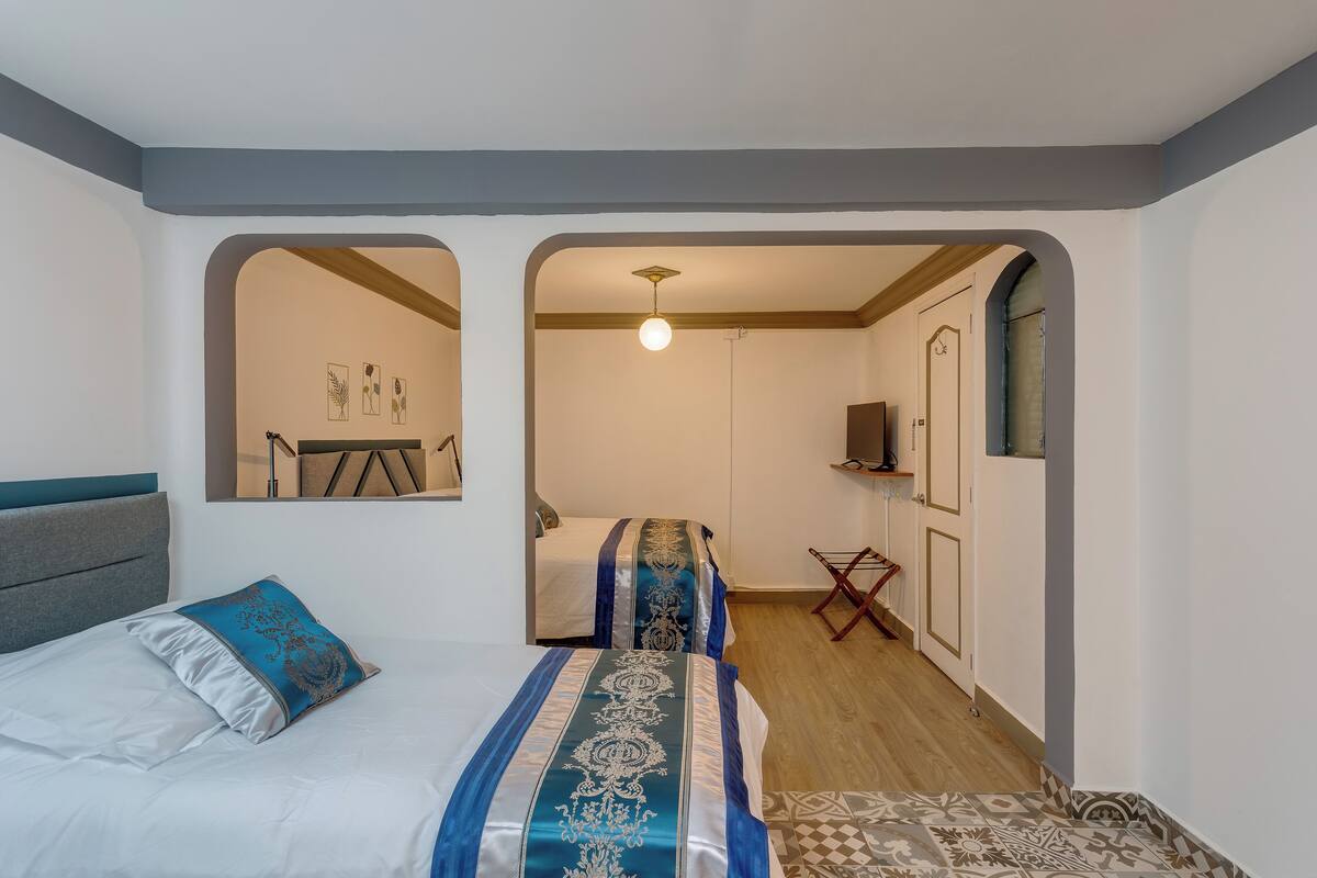 A bedroom with two beds, a desk, and a wardrobe.