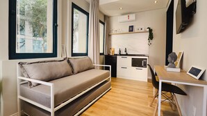 Un espacio habitable compacto con sofá, una mesa de comedor y zona de cocina.