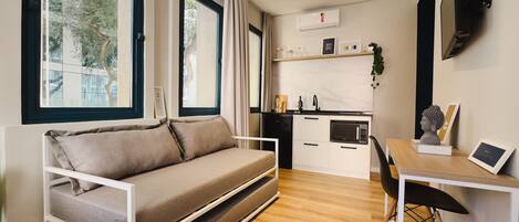 Un espacio habitable compacto con sofá, una mesa de comedor y zona de cocina.
