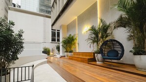 Un moderno vestíbulo interior con un mostrador de recepción de madera, una zona de estar y plantas en macetas.