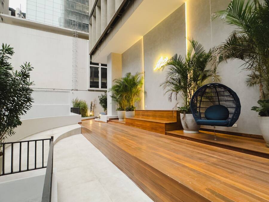 Un moderno vestíbulo interior con un mostrador de recepción de madera, una zona de estar y plantas en macetas.