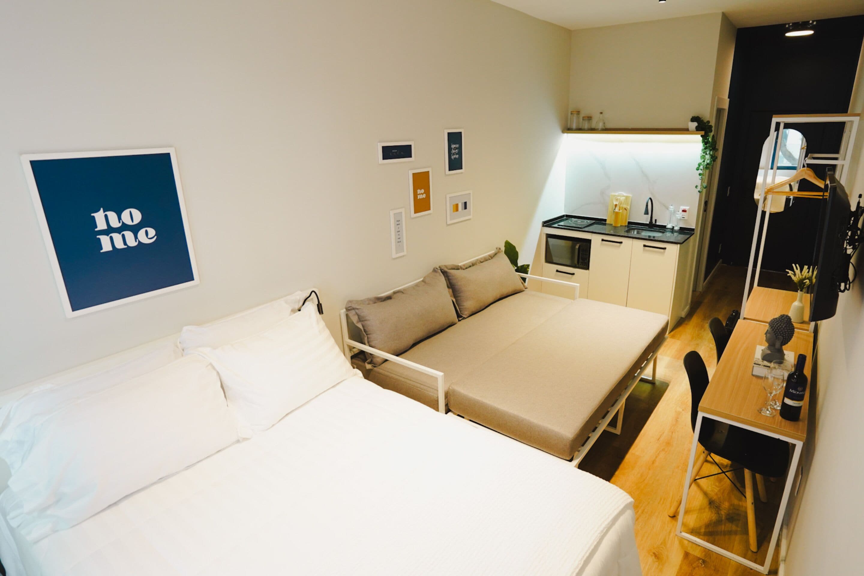 Une chambre d’hôtel compacte comprenant un lit, une petite kitchenette et un coin repas.