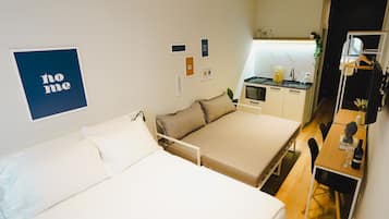 Ett kompakt hotellrum med en säng, ett litet pentry och en matplats.