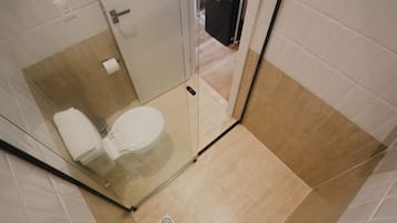 Une salle de bain avec une douche à parois de verre, des toilettes et un lavabo.
