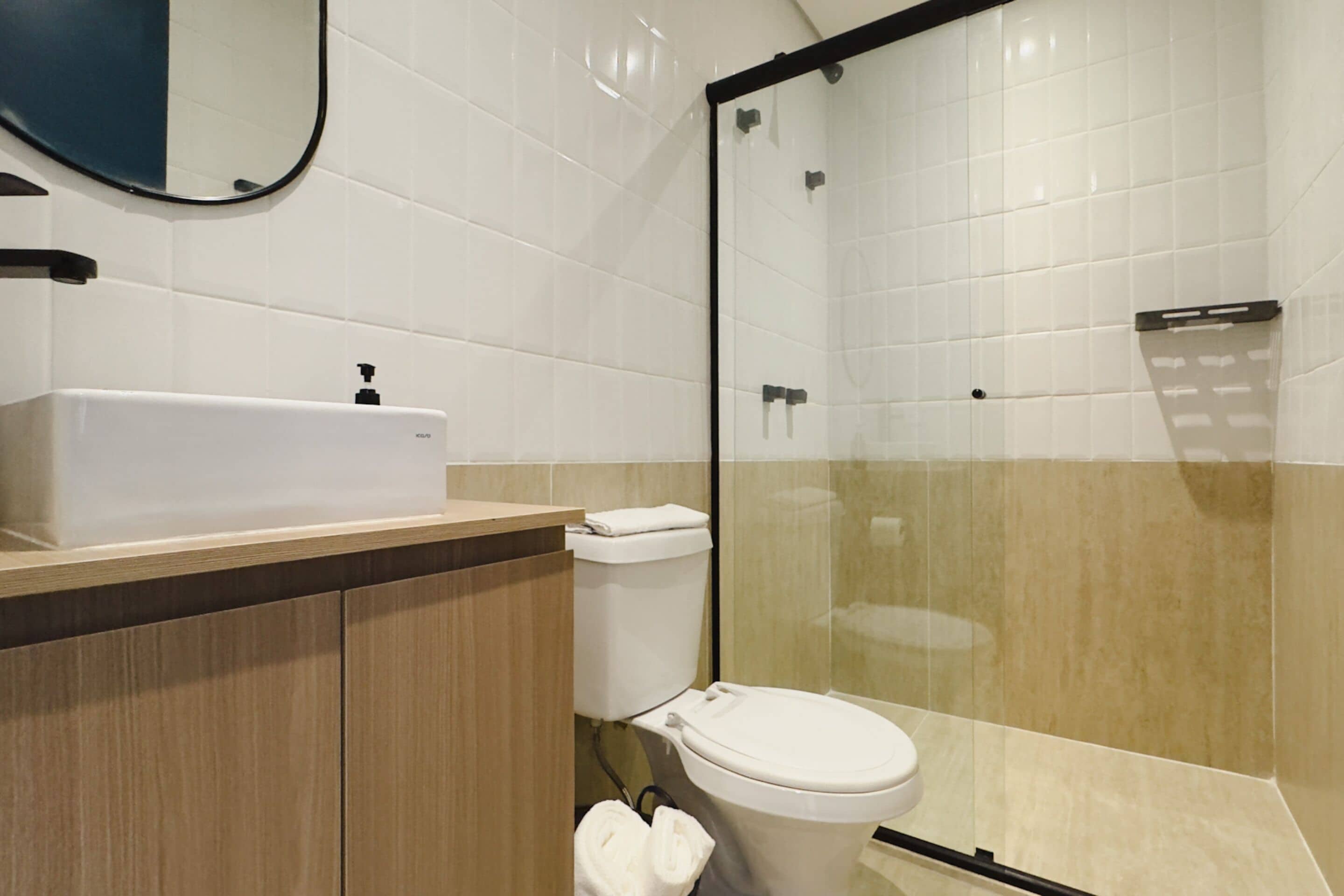 A modern bathroom with a white sink, toilet, and glass shower enclosure.