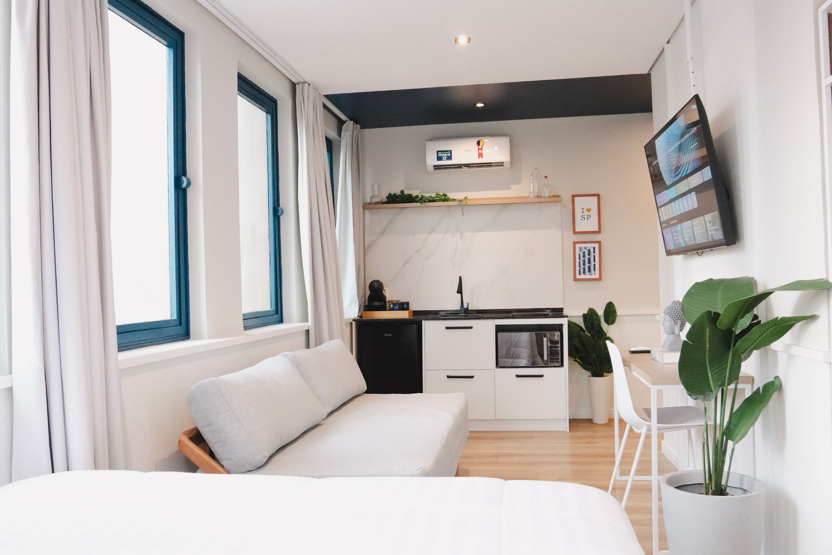 A modern room with a bed, a small kitchen area, and a dining table.