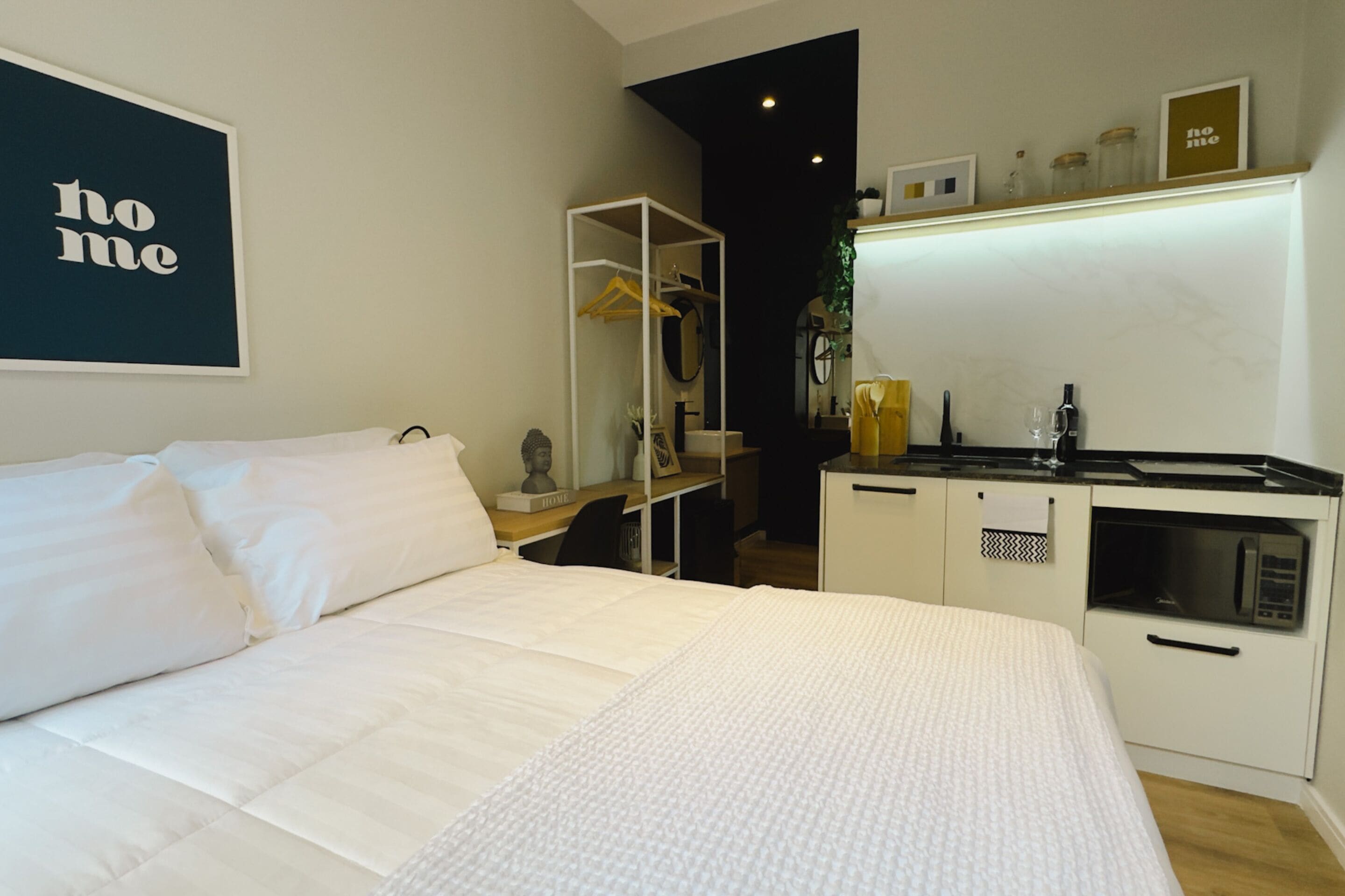 Une chambre avec un lit, une petite kitchenette et un miroir.