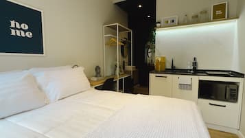 Une chambre avec un lit, une petite kitchenette et un miroir.