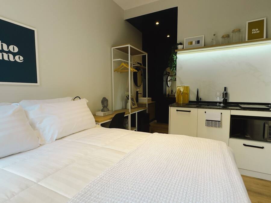 Une chambre avec un lit, une petite kitchenette et un miroir.