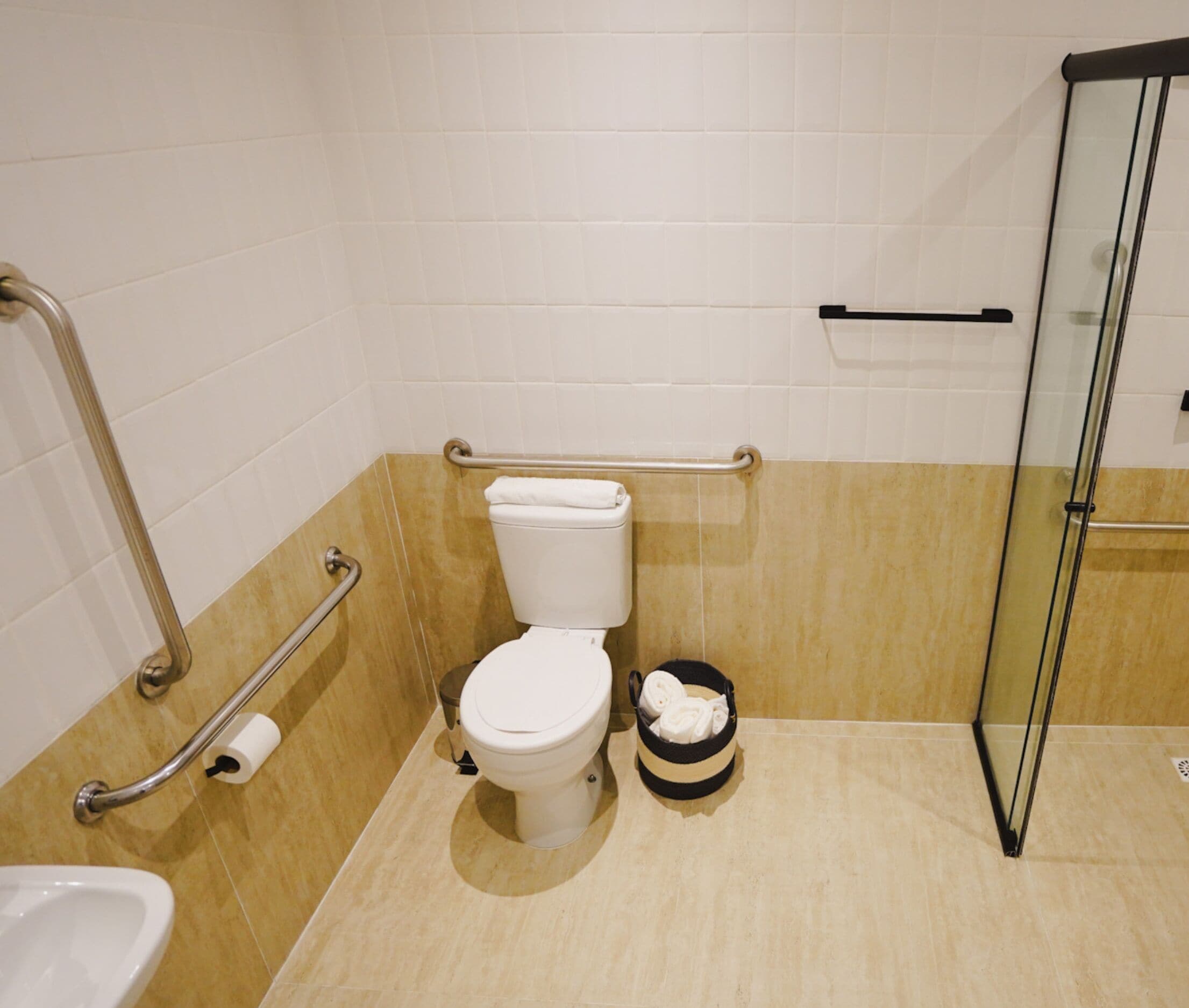 Une salle de bain avec des toilettes blanches, un bidet et une douche à parois de verre.