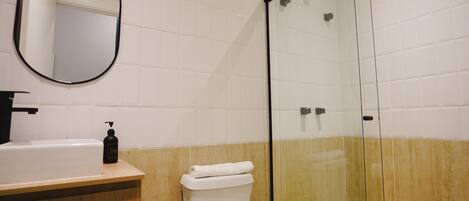 A bathroom with a sink, toilet, and a glass-enclosed shower.