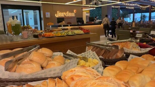 Un escaparate de panadería con diversos panes y pasteles, una barra con alimentos y un letrero que dice "Jardin".