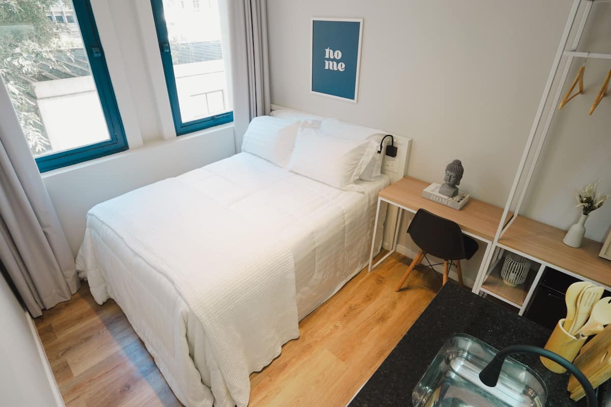 Ein ordentlich eingerichtetes Schlafzimmer mit Bett, Schreibtisch und Fenster.
