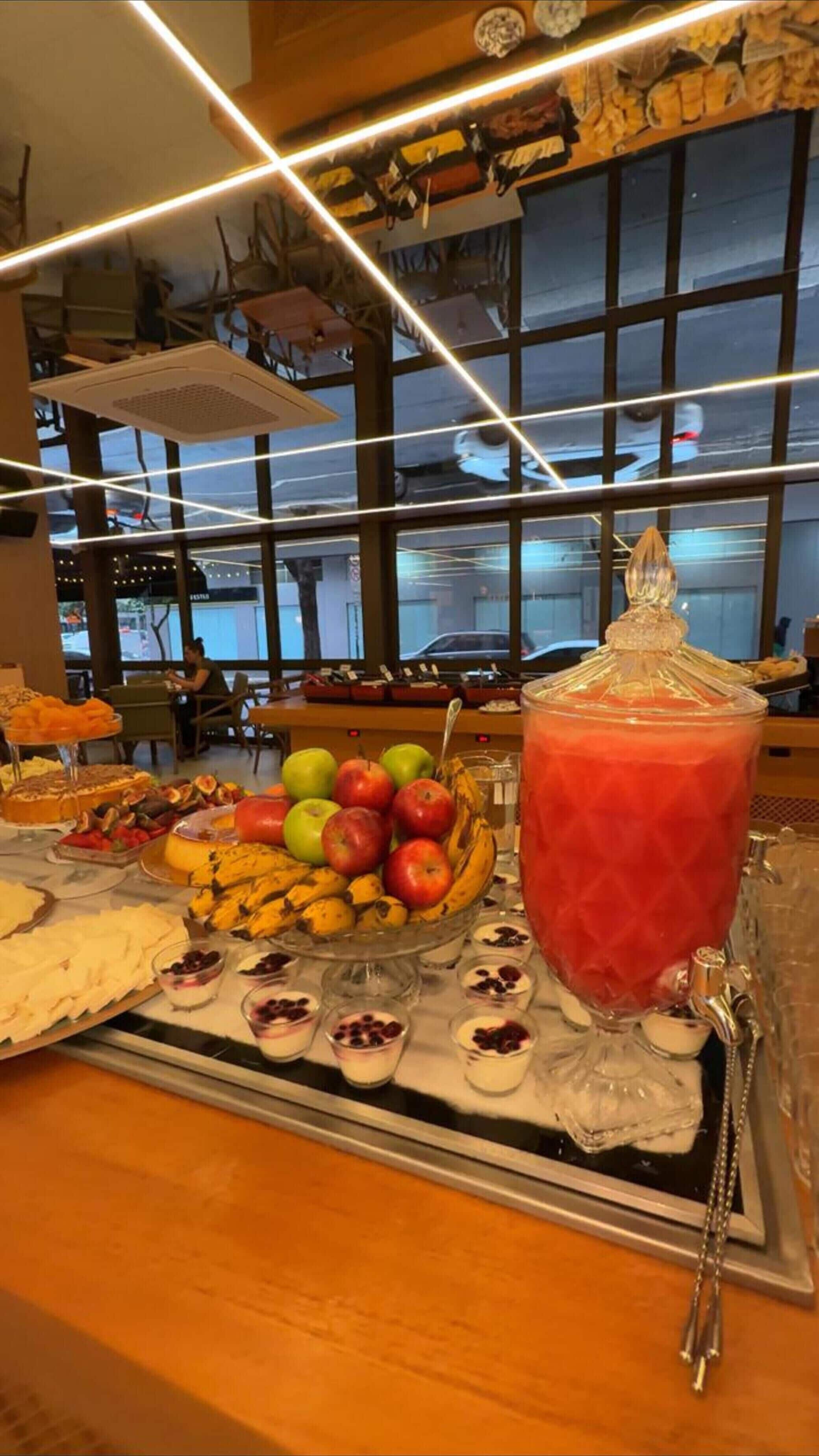 Una mesa de buffet con diversas frutas, postres y un gran bol de ponche de vidrio.