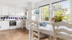 A modern kitchen with white cabinets, a built-in oven, and a dining area with a table and chairs.