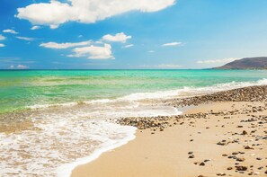 A beach with clear turquoise water, pebbly shore, and a mountain in the background. - Primrose home in Georgioupoli
 (GEORGIOUPOLI)