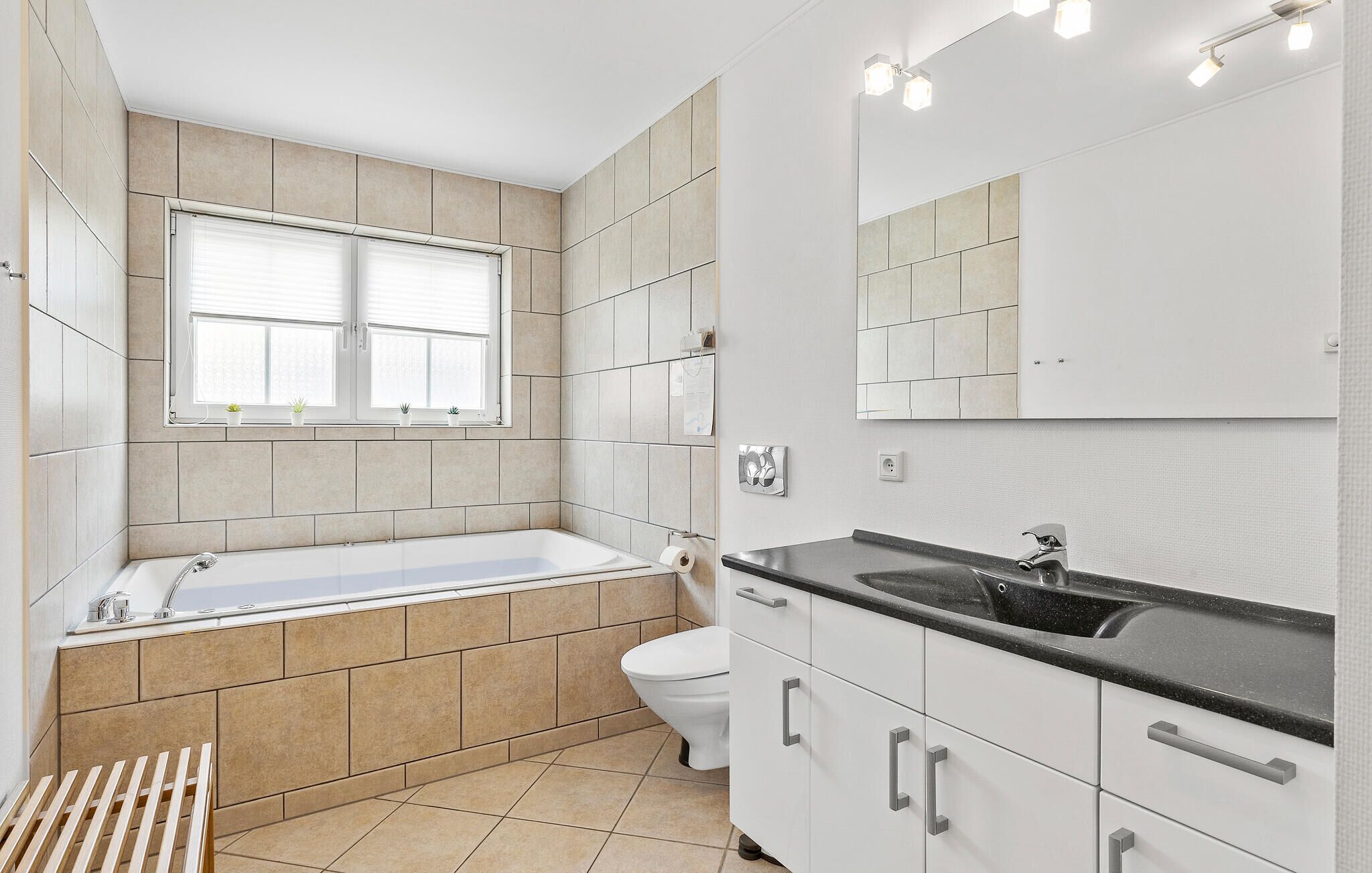 Un baño moderno con bañera, inodoro y tocador con lavamanos.