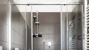 Ein modernes Badezimmer mit einer Glaskabine zur Dusche, einer weißen Toilette und einem Handtuchhalter.