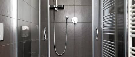 A modern bathroom with a glass-enclosed shower, a white toilet, and a towel rack.