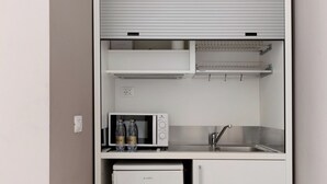Eine kleine Küchenzeile mit Mikrowelle, Kühlschrank und Spüle.