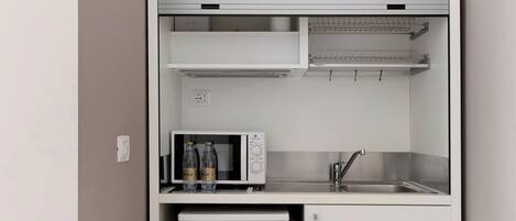 A compact kitchenette with a microwave, refrigerator, and sink.