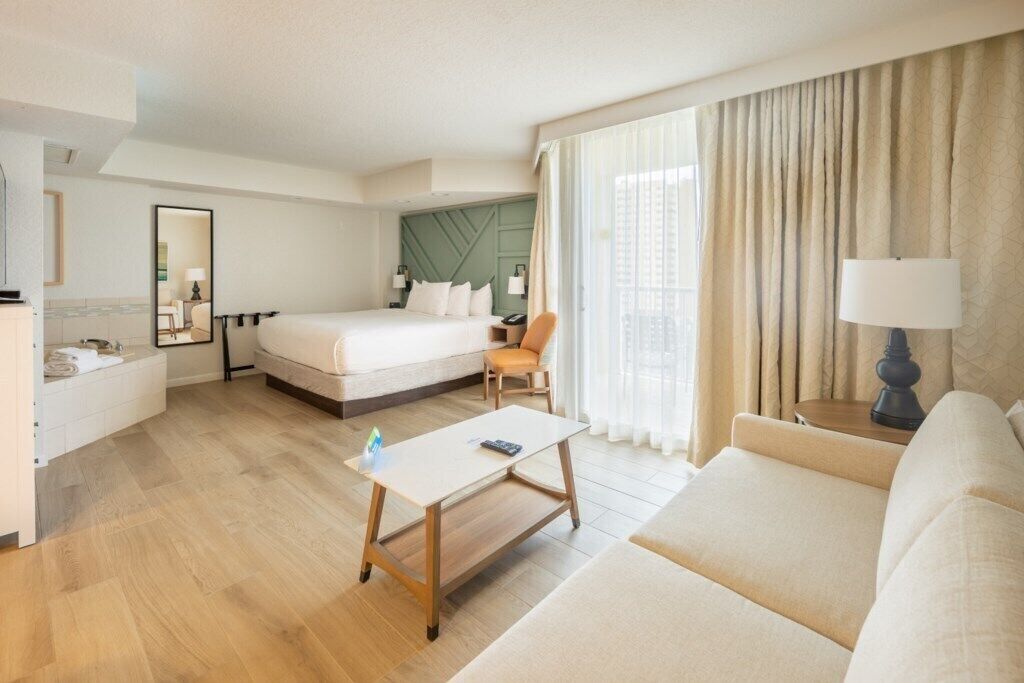 A hotel room with a bed, a sofa, a desk, and a chair.