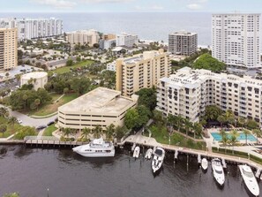 A coastal urban area with high-rise buildings, a marina with boats, and a large building with a flat roof. - Pompano Beach | Couples Ocean Weekend | Pool + Beach (Pompano)