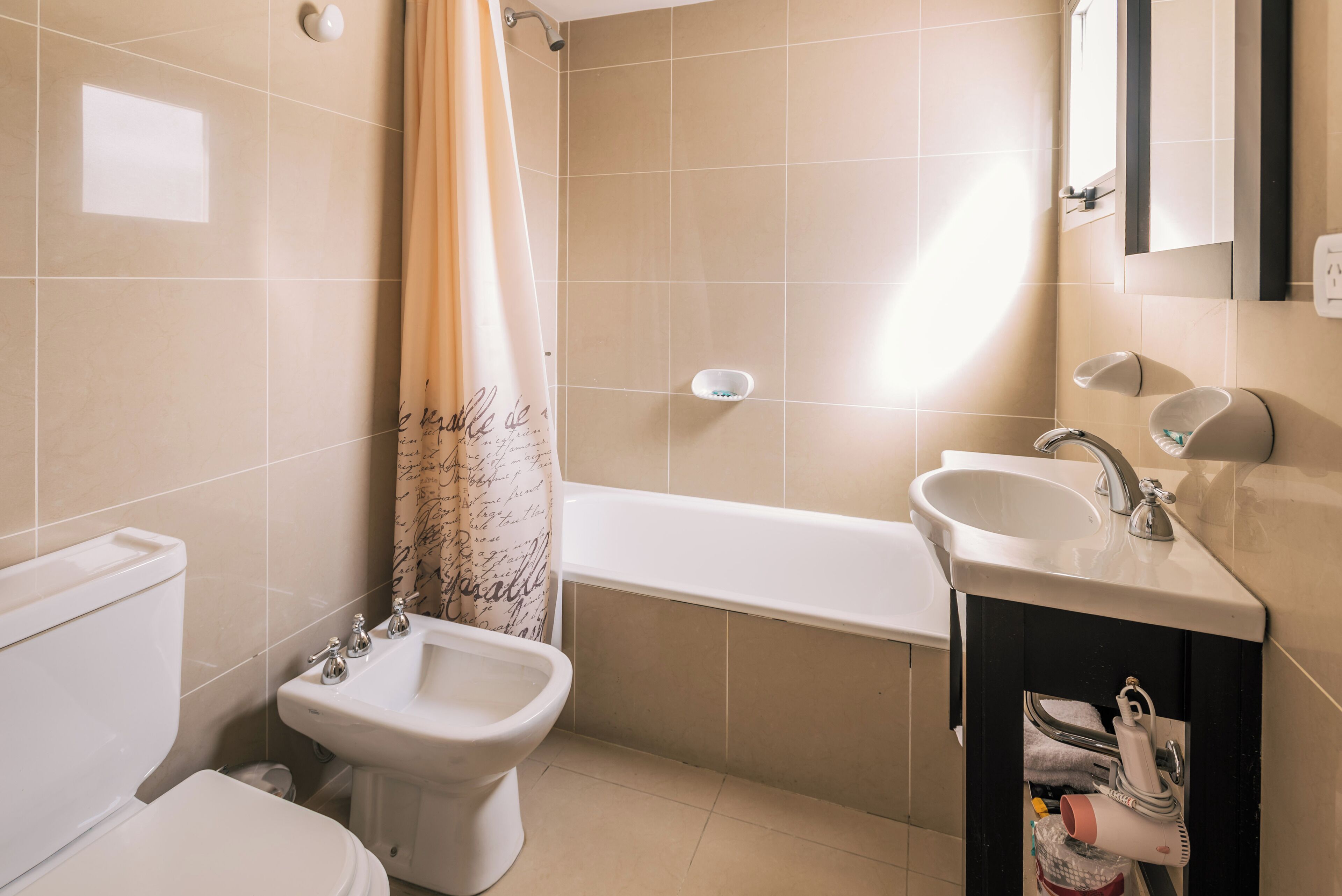 A bathroom with a toilet, bidet, bathtub, and sink.