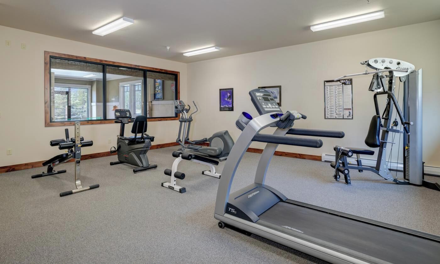 Un gimnasio con cintas de correr, máquinas de pesas y una máquina de remo.