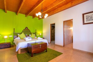 Ein Schlafzimmer mit Holzboden, einer grünen Wand, einem Bett mit Kissen, einem Nachttisch und einer Lampe.