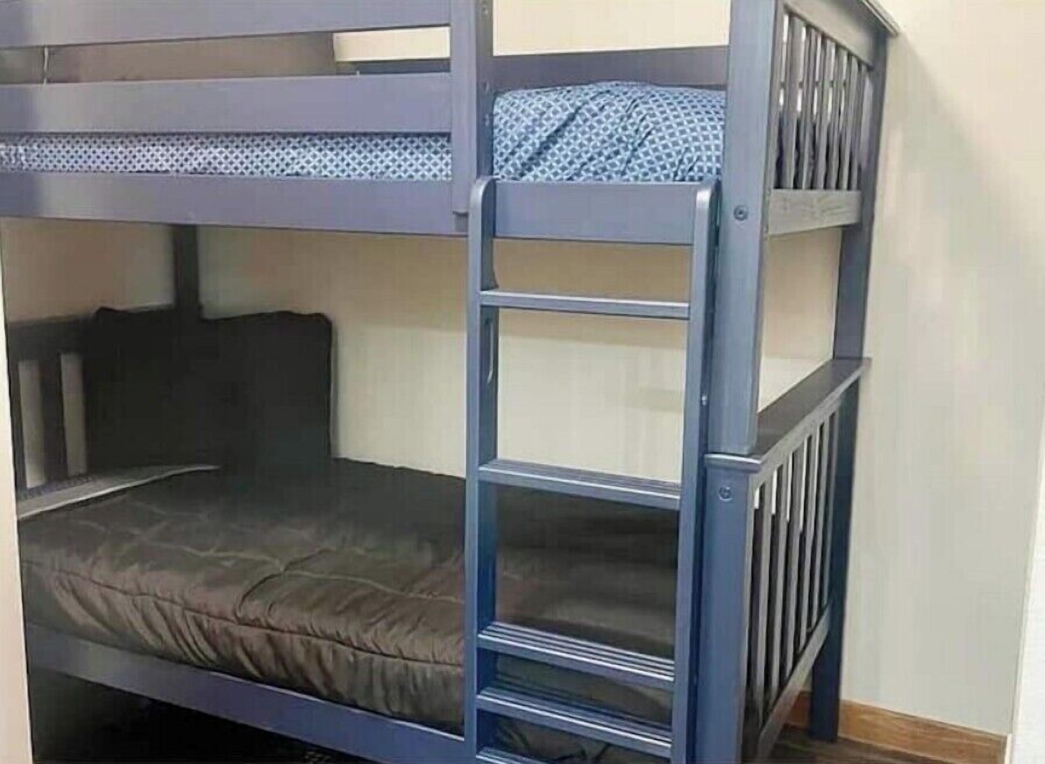 A bunk bed with a ladder, a mattress, and a headboard.