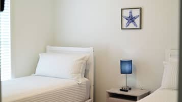 A bedroom with two beds, a nightstand with a lamp, and a framed starfish decoration on the wall.