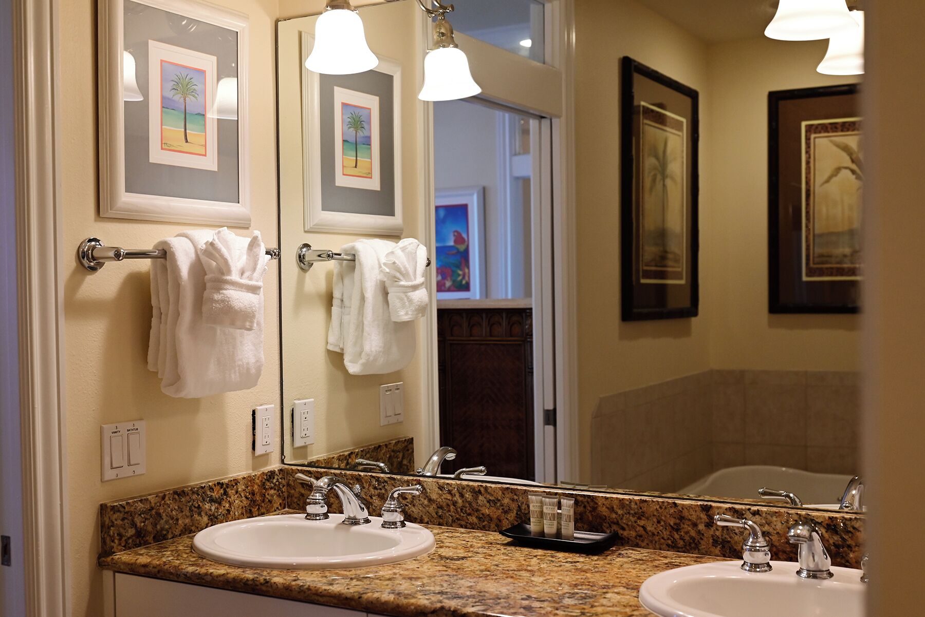 A bathroom with two sinks, a large mirror, and towels hanging on a rack.