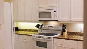 Eine Küche mit weißen Schränken, einer Mikrowelle, einem Backofen und Granit Arbeitsplatten.