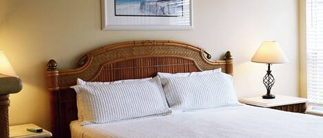 Habitación de hotel con cama, dos lámparas de noche, un cuadro en la pared y una ventana con persianas.