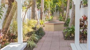A garden pathway with white benches and a central planter.