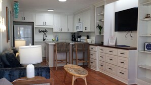 Une cuisine moderne avec des meubles blancs, un îlot central et des tabourets de bar.