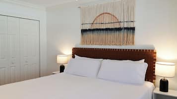 A hotel room with a large bed, two bedside lamps, a wooden headboard, and a wall-mounted tapestry.
