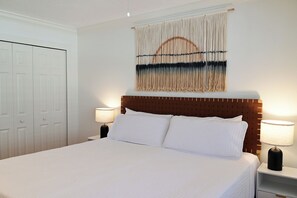 Ein Hotelzimmer mit einem großen Bett, zwei Nachttischlampen, einem hölzernen Kopfteil und einem Wandteppich.