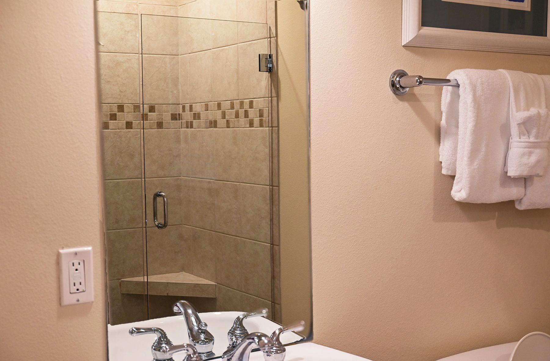 A bathroom with a shower, a sink, and a towel rack.