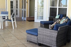 Een terras met rieten meubels, een tafel en stoelen.
