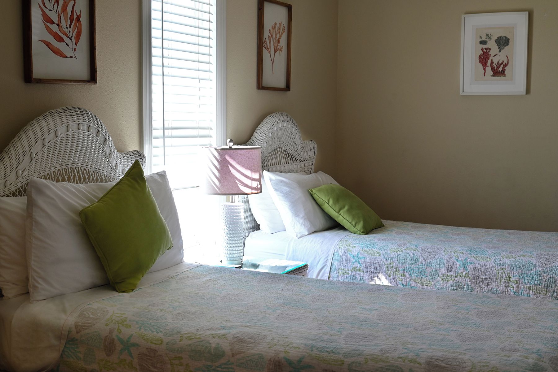 A bedroom with two beds, white bedding, and a bedside lamp.